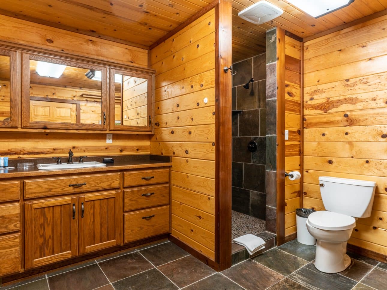 The beautiful master bathroom of the Mountain Sunset Cabin with slate and river rock walk-in shower.