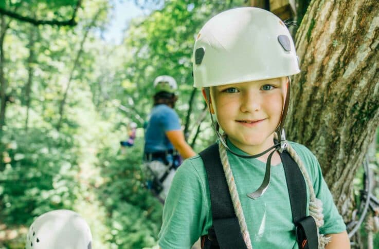 A kid smiles while on the platform of the Buffalo River Canopy Tour.